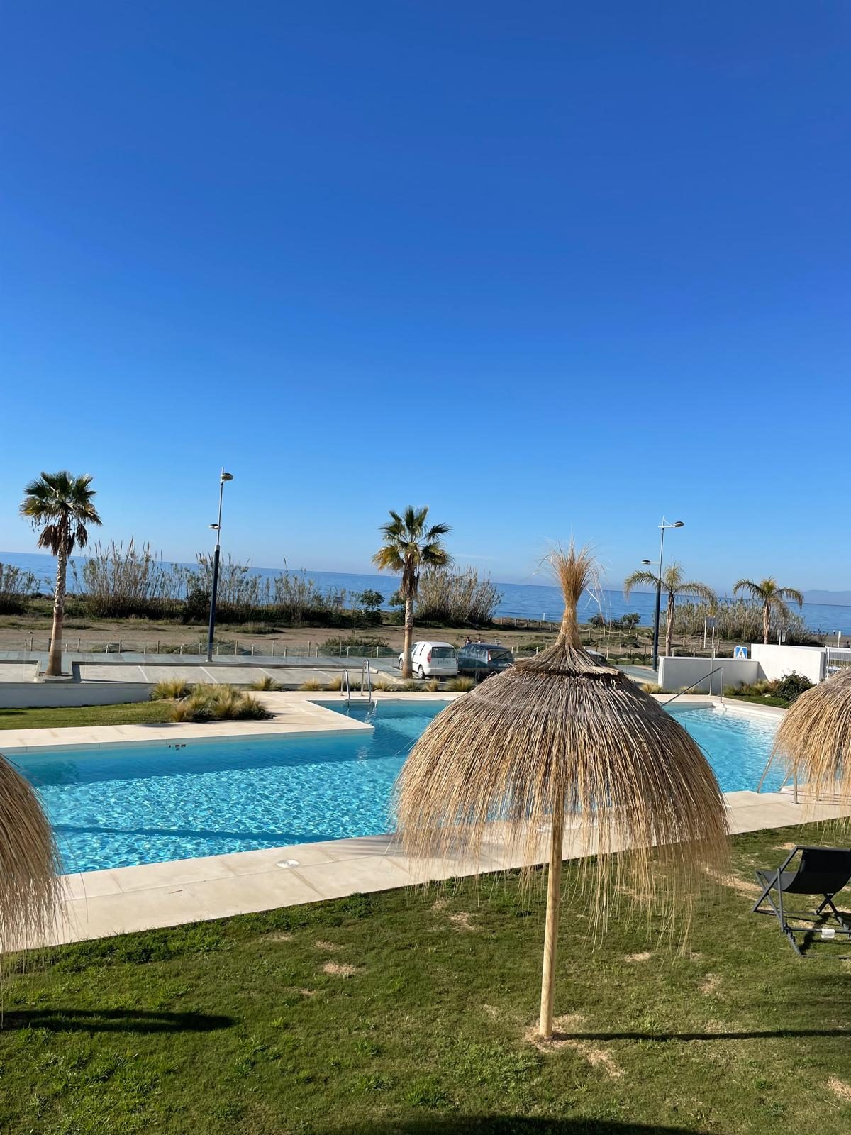 Piscina, césped y el mar al fondo, apartamento Mar de Dunas en Torrox Costa